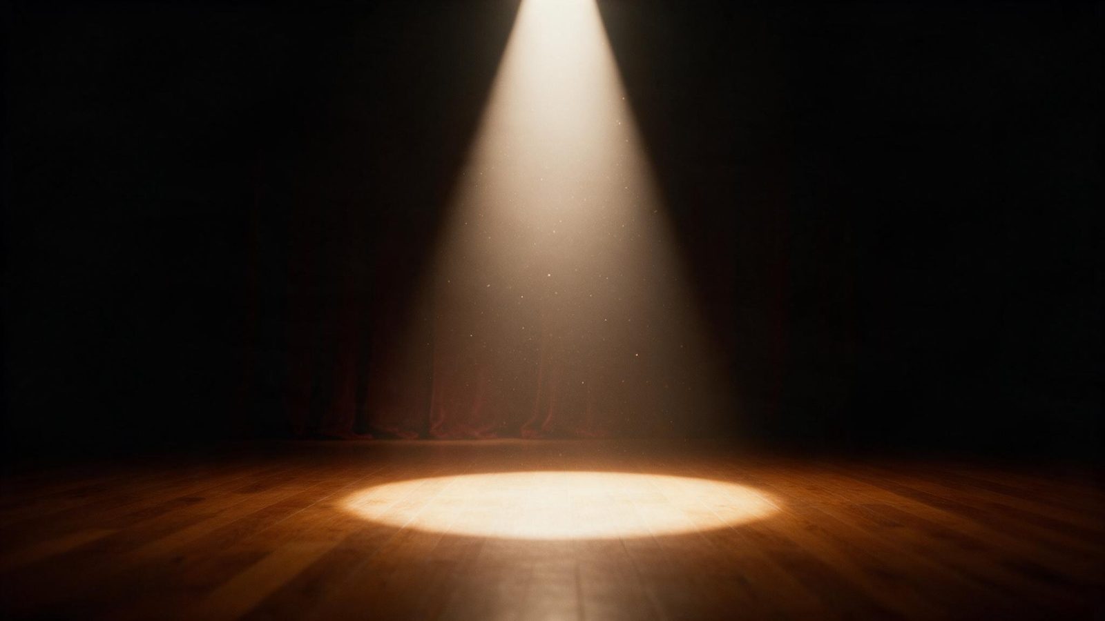 Un haz de luz de escenario iluminando el suelo de madera de un teatro vacío antes de la función